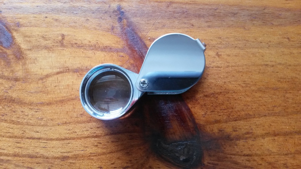 A simple 10x power folding hand lens, typical of the ones geologists carry into the field. 